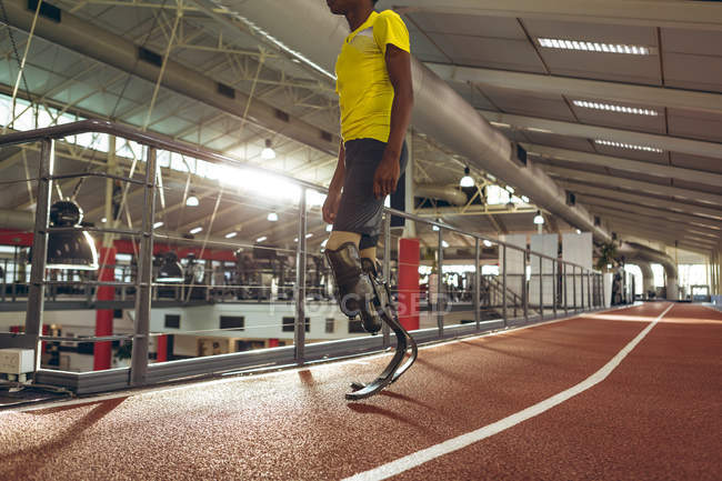 Low section of disabled African American male athletic standing on running track in fitness center — Stock Photo