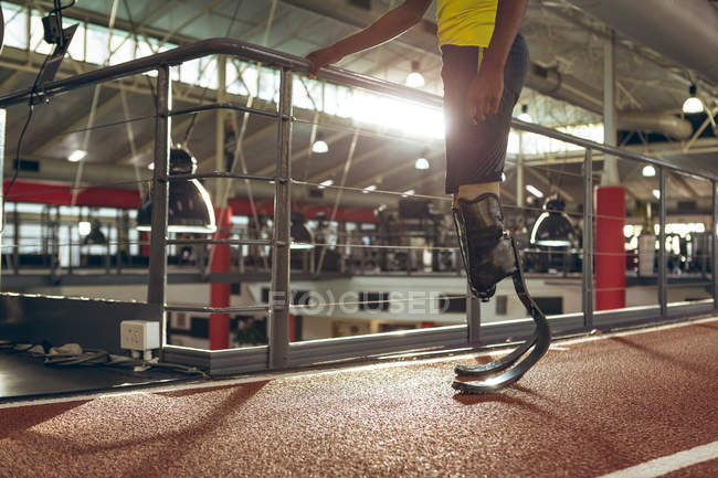 Sección baja de hombre discapacitado atlético de pie en pista de atletismo en el gimnasio - foto de stock