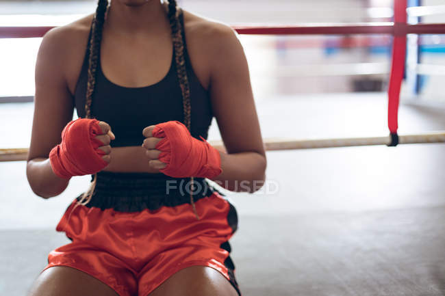 Parte média do boxeador feminino na mão envolve perto do ringue de boxe no clube de boxe. Forte lutador feminino no treinamento de ginásio de boxe duro . — Fotografia de Stock