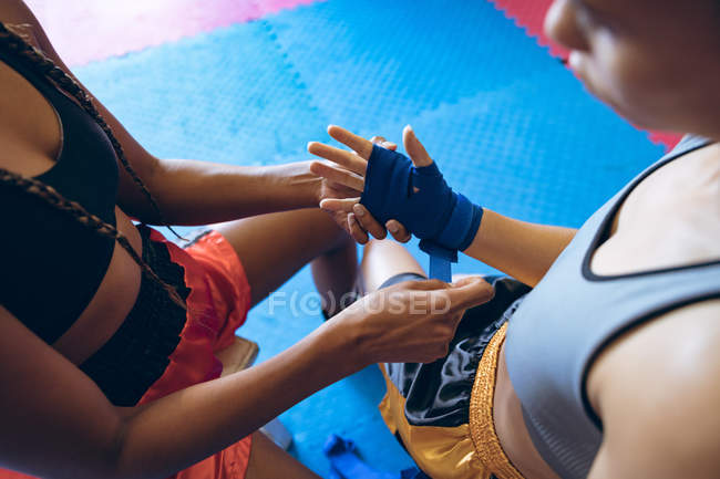 High angle view of female trainer putting hand wrap to female boxer in boxing club. Strong female fighter in boxing gym training hard. — Stock Photo