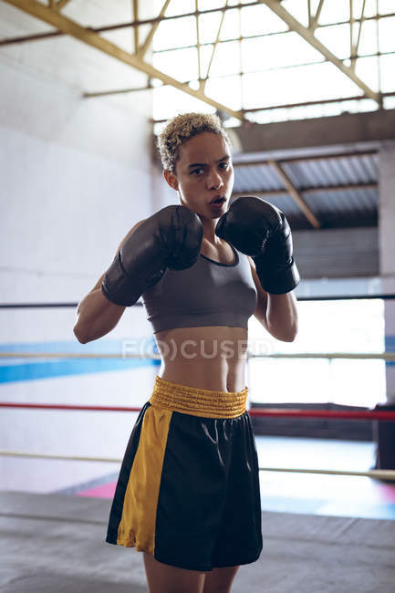 Front view of female boxer practicing boxing in boxing club. Strong female fighter in boxing gym training hard. — Stock Photo
