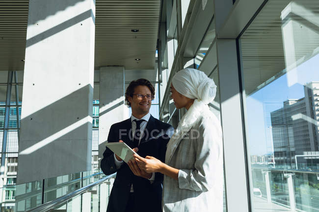 Happy business people working together on digital tablet in corridor at modern office. — Stock Photo