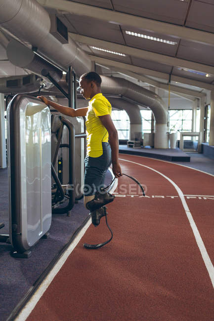 Athlétisme masculin handicapé afro-américain réfléchi debout sur la piste de course dans un centre de fitness — Photo de stock
