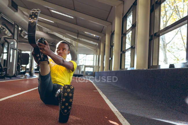 Вид спереди на инвалида афроамериканского спортсмена, занимающегося спортом на беговой дорожке в фитнес-центре — стоковое фото