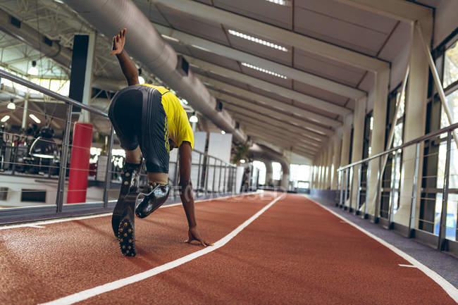Vista posteriore della corsa atletica maschile afroamericana disabile in pista nel centro fitness — Foto stock