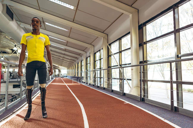 Frontansicht eines behinderten afrikanisch-amerikanischen männlichen Athleten, der auf der Laufbahn im Fitness-Center steht — Stockfoto