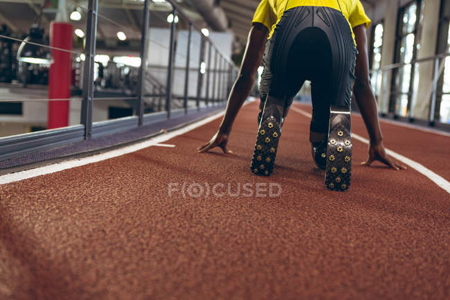Visão traseira do atlético masculino com deficiência na posição inicial na pista de corrida no centro de fitness — Fotografia de Stock