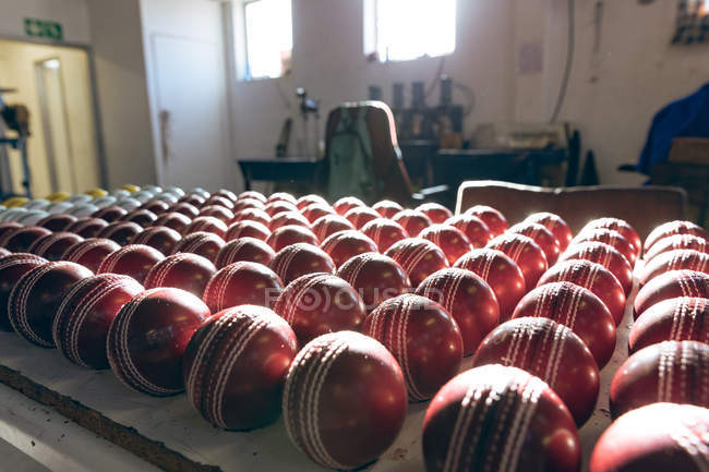 Close up of red cricket balls in rows at the end of the production line in the workshop at a factory that produces them. — Stock Photo