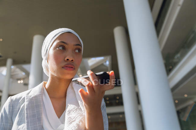 Низький кут зору ділової жінки в хіджабі говорити на мобільному телефоні в сучасний офіс. — стокове фото