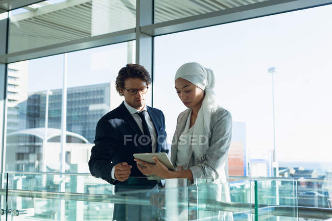 Front view of business people working together on digital tablet in corridor at modern office. — Stock Photo