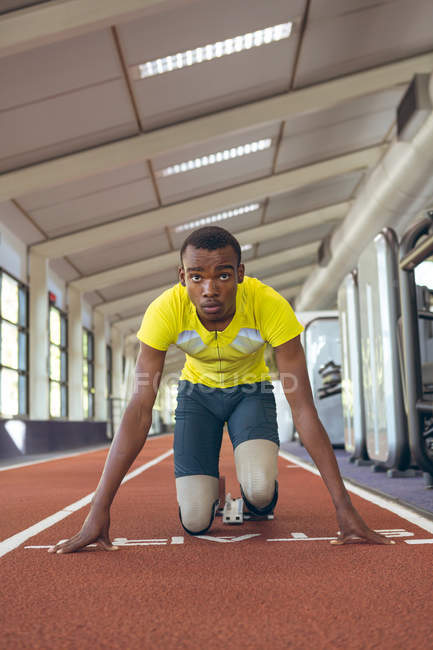 Vorderansicht des behinderten afrikanisch-amerikanischen männlichen Athleten am Startpunkt auf der Laufbahn im Fitness-Center — Stockfoto