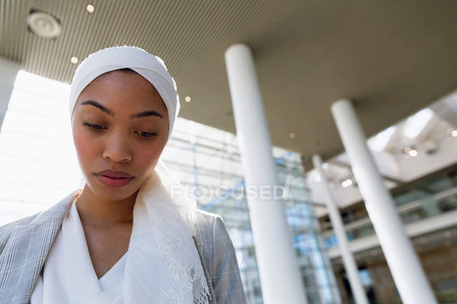 Niedrigwinkel-Ansicht einer Geschäftsfrau im Hidschab, die in einem modernen Büro nach unten schaut. — Stockfoto