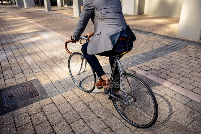 Rear view low section of a man riding his bicycle in a city street. Digital Nomad on the go. — Stock Photo