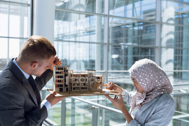 Multi-ethnic male and female architects discussing over construction project in office. — Stock Photo