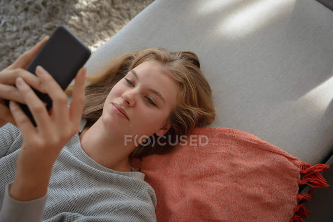 Overhead close up de uma jovem mulher caucasiana deitada em um sofá usando smartphone . — Fotografia de Stock