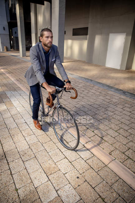 Front view close up of a young Caucasian man riding his bicycle in a city street. Digital Nomad on the go. — Stock Photo