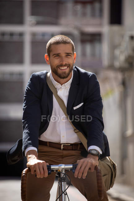 Вид спереди на улыбающегося молодого кавказца, едущего на велосипеде по городской улице. Цифровая реклама на ходу . — стоковое фото