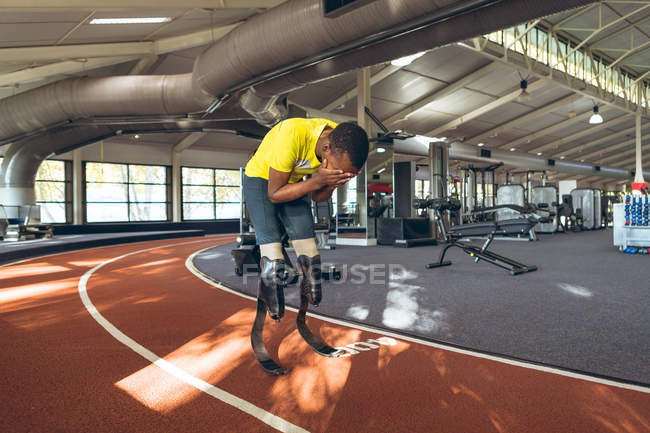 Vue de face de l'athlétisme masculin afro-américain handicapé déçu après avoir perdu la course dans un centre de fitness — Photo de stock