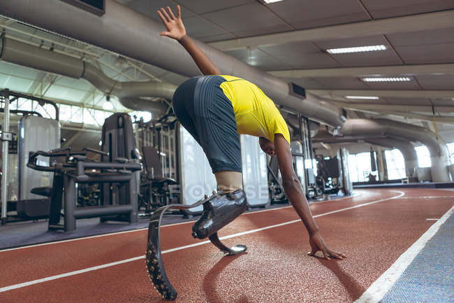 Visão traseira do atlético masculino afro-americano deficiente correndo em pista de esportes no centro de fitness — Fotografia de Stock