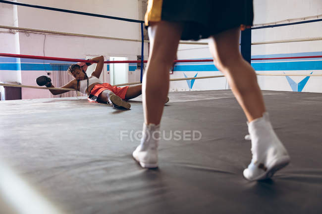 Boxer feminino inconsciente deitado no ringue de boxe no centro de fitness. Forte lutador feminino no treinamento de ginásio de boxe duro . — Fotografia de Stock