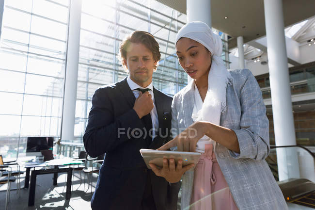 Low angle of business people working together on digital tablet in a modern office. — Stock Photo