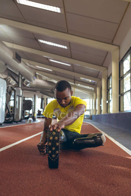 Vue de face de l'exercice athlétique masculin afro-américain handicapé sur piste de course dans le centre de remise en forme — Photo de stock