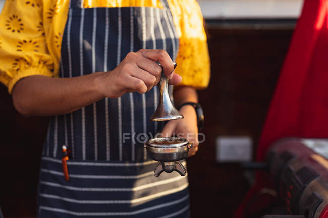 Front view mid section of woman wearing an apron preparing coffee in a food vending truck — Stock Photo