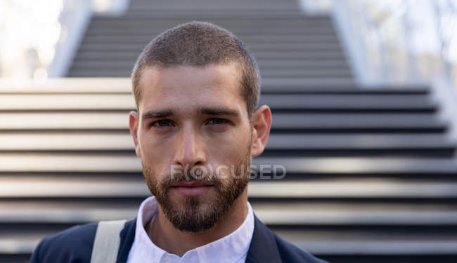 Portrait close up of a young Caucasian man standing in front of steps in a city street. Digital Nomad on the go. — Stock Photo