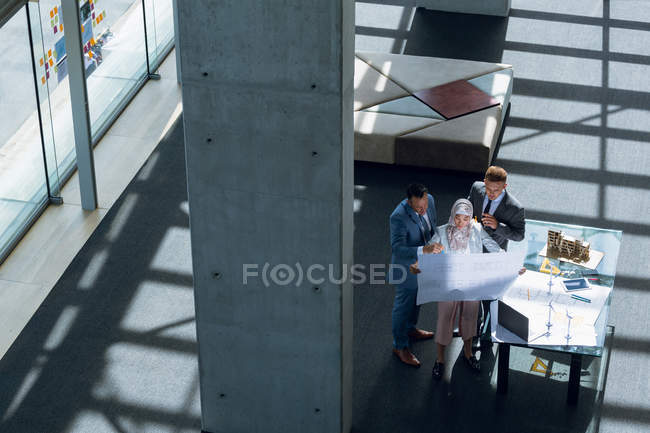 Multi-ethnic male and female architects discussing over blueprint in office. — Stock Photo