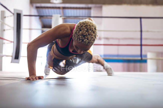 Boxeadora afroamericana ejercitándose en el ring de boxeo en el gimnasio. Fuerte luchadora en el boxeo gimnasio entrenamiento duro . - foto de stock