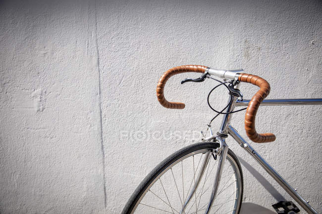 Seitenansicht eines Rennrads, das in einer Stadtstraße gegen eine Mauer gelehnt ist. Digitaler Nomade unterwegs. — Stockfoto