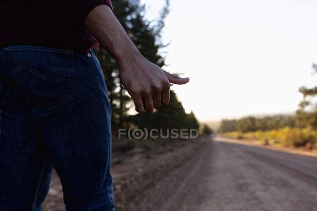 Low section of man hitchhiking on the road — Stock Photo
