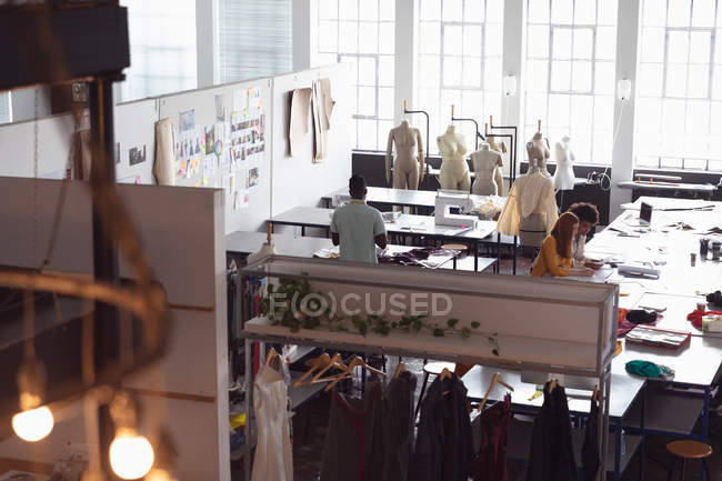Blick aus der Vogelperspektive auf eine Gruppe von Modestudenten, die in einem Atelier der Modehochschule an Designs arbeiten — Stockfoto