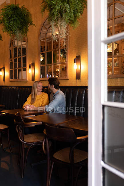 Vista lateral de um jovem casal caucasiano feliz relaxando juntos em férias em um bar, abraçando e de mãos dadas — Fotografia de Stock