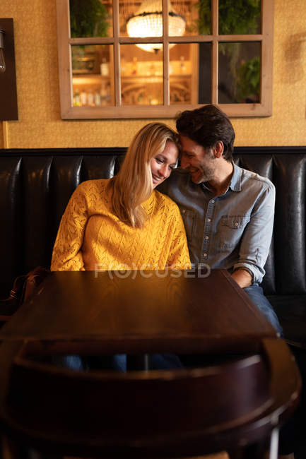 Vista frontal de um jovem casal caucasiano feliz relaxando juntos em férias em um bar, abraçando — Fotografia de Stock