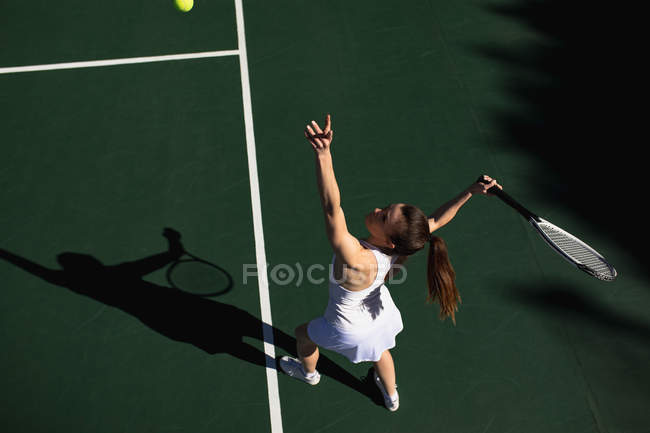 HIgh angle view of a young Caucasian woman playing tennis on a sunny day, serving — Stock Photo