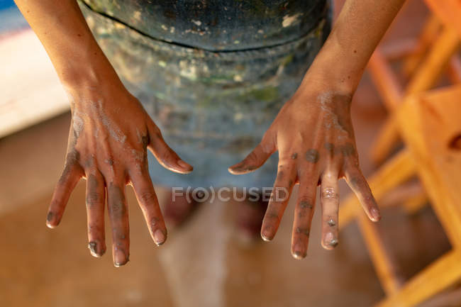 Elevado primer plano de las manos de alfarero femenino con arcilla en ellos en un estudio de cerámica - foto de stock