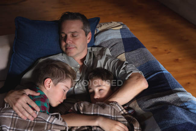 Front view of a middle aged Caucasian man and his pre teen sons sleeping on a couch — Stock Photo