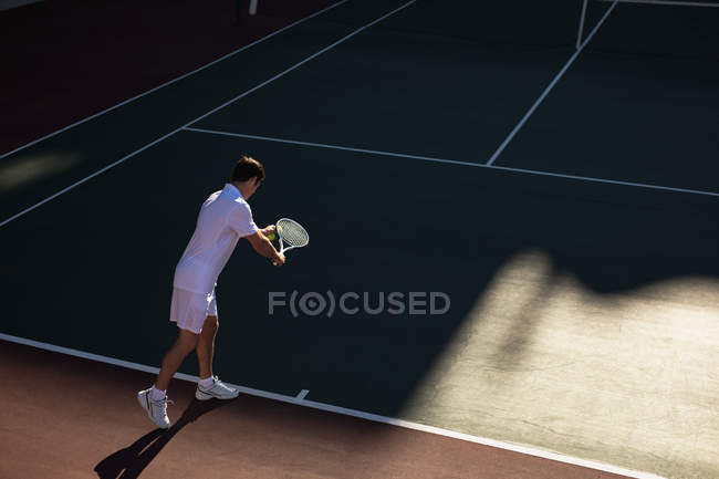 Rear view of a young Caucasian man playing tennis, preparing to serve — Stock Photo