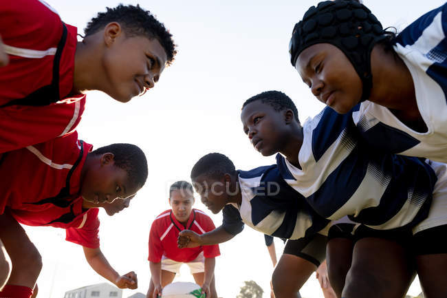 Vue de côté gros plan de deux équipes opposées de jeunes joueuses de rugby multiethniques adultes attendant que le ballon soit lancé avant une mêlée lors d'un match de rugby — Photo de stock