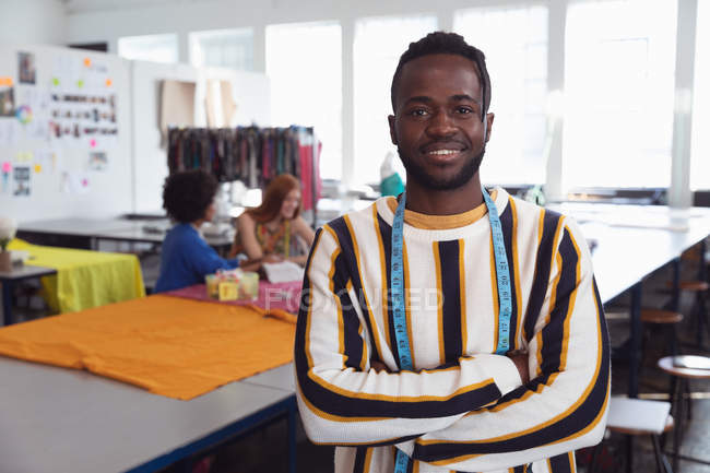 Retrato de um jovem afro-americano estudante de moda do sexo masculino de pé com os braços cruzados em um estúdio na faculdade de moda — Fotografia de Stock