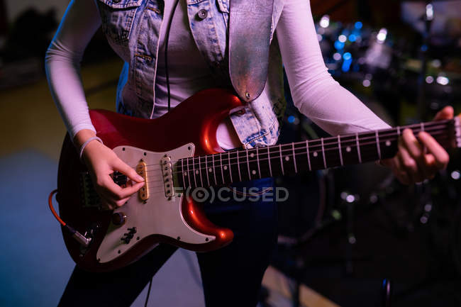Vista frontal sección media de la mujer tocando una guitarra eléctrica durante una sesión en un estudio de grabación - foto de stock