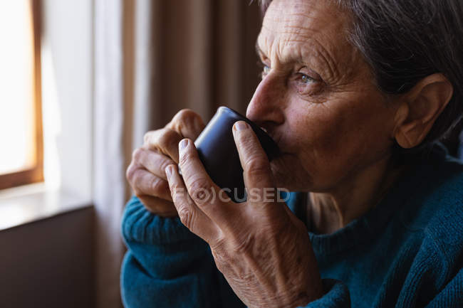 Вид збоку крупним планом старший кавказька жінка пити каву в домашніх умовах — стокове фото