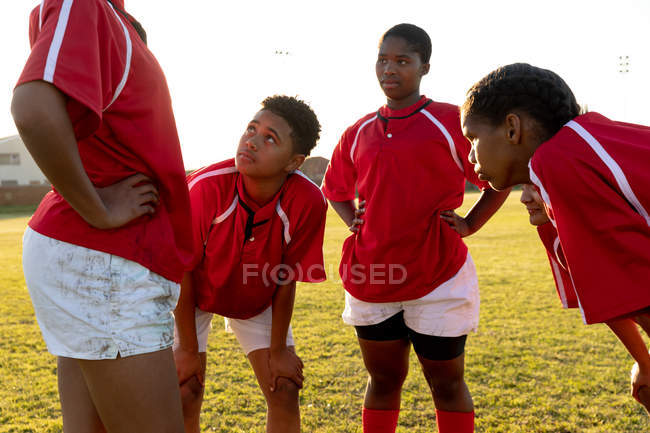 Seitenansicht einer Mannschaft junger erwachsener multiethnischer Rugbyspielerinnen, die nach einem Rugbyspiel auf einem Rugbyplatz stehen und sich unterhalten und entspannen. — Stockfoto