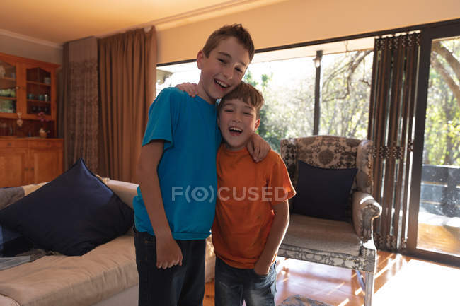 Porträt zweier kaukasischer Jungs im Wohnzimmer zu Hause, die in die Kamera schauen — Stockfoto