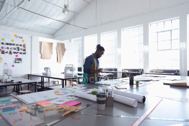 Seitenansicht eines jungen afrikanisch-amerikanischen männlichen Modestudenten, der in einem Atelier der Modehochschule an einem Design arbeitet — Stockfoto