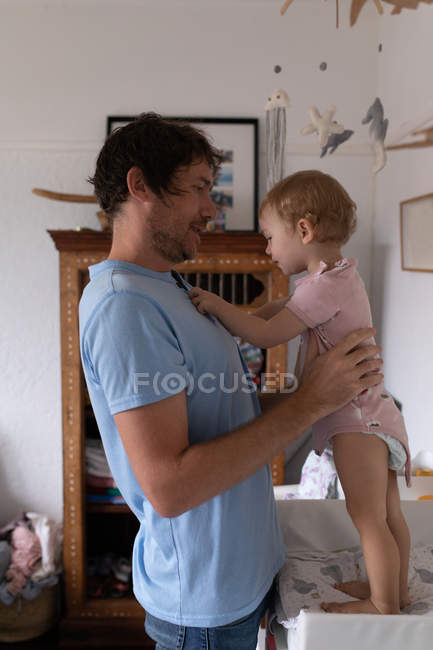 Side view of a young Caucasian father getting his baby dressed on a changing mat — Stock Photo