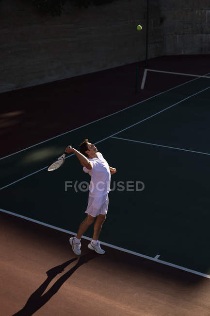 Вид сбоку на молодого кавказца, играющего в теннис, служащего — стоковое фото