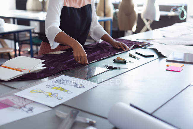Front view mid section of female fashion student measuring fabric on a table while working on a design in a studio at fashion college — Stock Photo