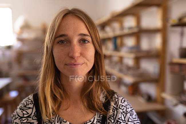 Portrait close up of a young Caucasian female potter standing in a pottery studio — Stock Photo